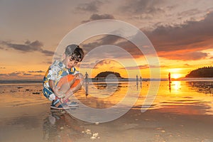 A cute boy playing sand in sunset