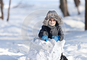 Cute boy playing with snow in the winter park