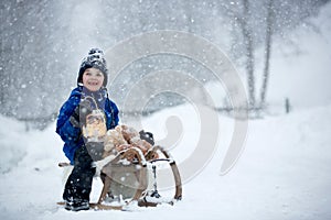 Cute boy playing with teddy bear in the snow, winter time. Little toddler playing with toys on snowy day