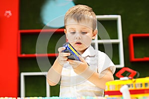 Cute boy playing with tram. Little boy playing with car toy.