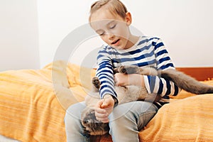 Cute boy plays with a cat at home. Happy kid hugging his cat