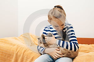 Cute boy plays with a cat at home. Happy kid hugging his cat