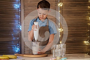 a cute boy prepares a milkshake with a banana.
