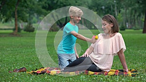 Cute boy presenting wildflowers to mother, pleasant surprise from loved one