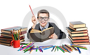 Cute boy reading a book with glasses. Happy child sitting with a book at the table.
