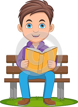 cute boy reading a book while sitting on a bench
