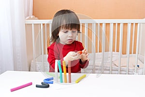 Cute boy in red shirt playing with playdough