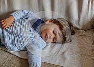 Cute boy rests peacefully on sofa in the living room of his house