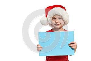 Cute boy in Santa hat with a blank blue board in his hands. Isolate on white