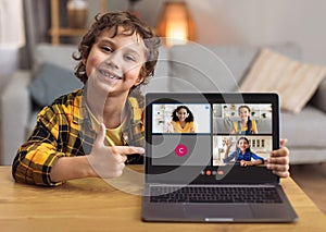 Cute boy schooler showing laptop with online lesson screen