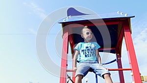 Cute boy of seven years having fun on a playground outdoors in summer. Slow motion . Joyful active childhood.