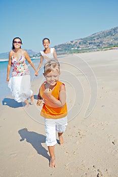 Cute boy with sister and mother on the beach