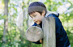 Cute boy with smiling face looking out, Candid shot happy kid playing in the park,Child having fun in a climbing on wooden fame