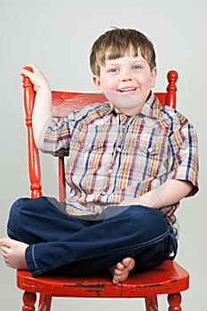 Cute boy smiling on orange chair