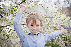 Cute boy among spring blooming tree