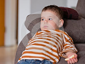 cute boy in a striped shirt eating cheesecake while watching TV