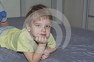 A cute boy in a striped T-shirt. Portrait of a blond boy in a natural setting. The face expresses natural emotions