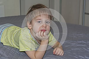 A cute boy in a striped T-shirt. Portrait of a blond boy in a natural setting. The face expresses natural emotions