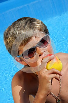 Cute Boy with sun glasses eating a delicious apple