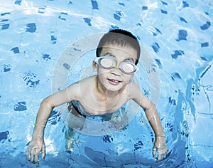 Cute boy swimming and playing in swimming pool