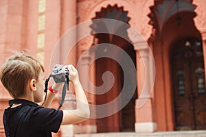 Cute boy takes pictures of sights. School project for kids for summer vacations. Summer holidays, memories and impressions