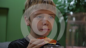 Cute boy taking big bite of cheese pizza at restaurant. Hungry kid boy eating fast food at pizzeria