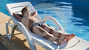 Cute boy taking sun near a swimming pool