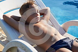 Cute boy taking sun near a swimming pool