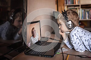 Cute boy talking with his grandmother within video chat on laptop, life in quarantine time