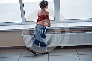 Cute boy waiting at airport looking at window and enjoying planes arriving, rear view