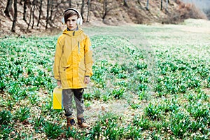 Cute boy walking at nature. Kid with headphones relaxing in the spring park