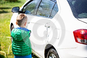 Cute boy washing car outdoors