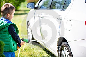 Cute boy washing car outdoors