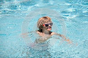 Cute boy in the water playing with water. Funny cute little boy in sunglasses in pool in sunny day. Child relax in
