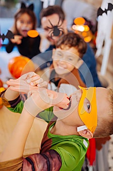 Cute boy wearing Ninja turtle costume for Halloween playing tricks eating sweets