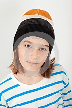 Cute boy wearing stylish woolen hat. Kid posing over white background