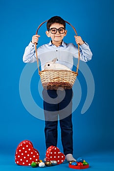 Cute boy with White rabbit in basket with Easter eggs