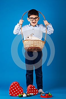 Cute boy with White rabbit in basket with Easter eggs