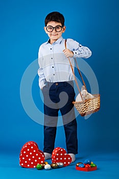 Cute boy with White rabbit in basket with Easter eggs