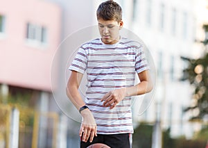 Cute boy in white t shirt plays  basketball on street  playground. Teenager  throws orange basketball ball outside. Hobby,