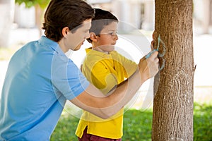 Cute boy writing his name on a tree