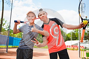 Cute boys playing tennis and posing in court outdoor