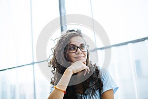 Cute brazilian girl with curly hair listening to a conversation and has an idea