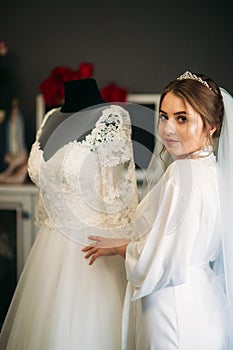 Cute bride dressed at home in a wedding dress