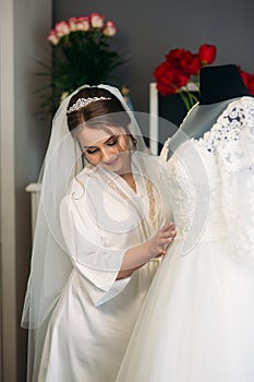 Cute bride dressed at home in a wedding dress