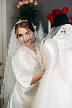 Cute bride dressed at home in a wedding dress