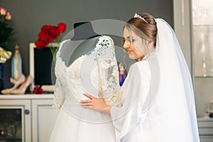 Cute bride dressed at home in a wedding dress