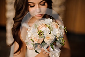 Cute bride holding wedding bouquet of white and peach roses