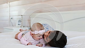 Cute brother plays with his little sister on a bed at home