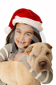 Cute brunette girl holding a Shar Pei puppy wearing a santa hat